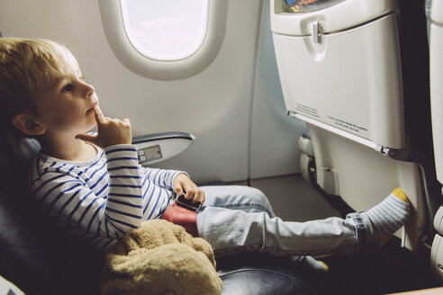 Nachdenklicher kleiner Junge in einem Flugzeug sitzend - MFF001991