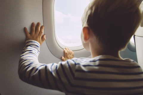 Little boy looking out of window while flying on an airplane stock photo
