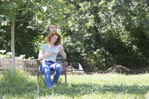Junge Frau liest im Garten, lizenzfreies Stockfoto