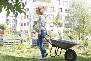 Junge Frau bei der Gartenarbeit, Urban Gardening, Schubkarre - SGF001820