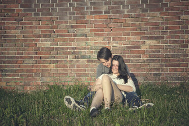 Couple sitting on brick roman wall undefined. Men in blue jeans and brown  boots, woman in black leggings and sneakers, orange wall as a bench Stock  Photo - Alamy