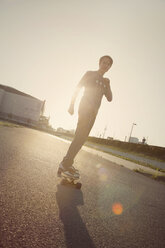 Teenage boy on a longboard at backlight - MMFF000973