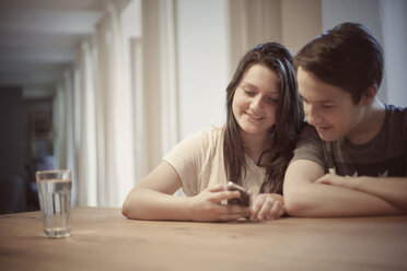 Teenagerpaar mit Smartphone zu Hause - MMFF000977