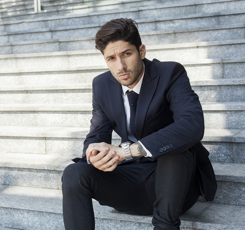 Porträt eines jungen Geschäftsmannes auf der Treppe sitzend, lizenzfreies Stockfoto