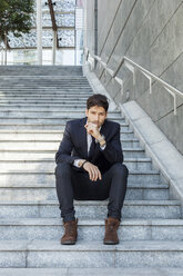 Porträt eines jungen Geschäftsmannes auf einer Treppe sitzend - PASF000006