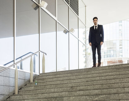 Porträt eines jungen Geschäftsmannes am oberen Ende einer Treppe - PASF000009