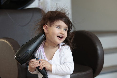 Porträt eines kleinen Mädchens mit Haartrockner, lizenzfreies Stockfoto