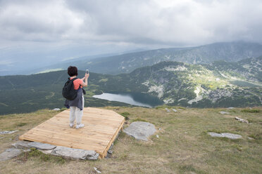 Bulgarien, Rila-Gebirge, Rückenansicht einer älteren Frau beim Fotografieren mit dem Smartphone - DEGF000492