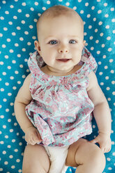 Portrait of baby girl lying on her back on dotted blanket - MFF001954