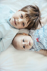Baby girl and brother lying on bed - MFF001963