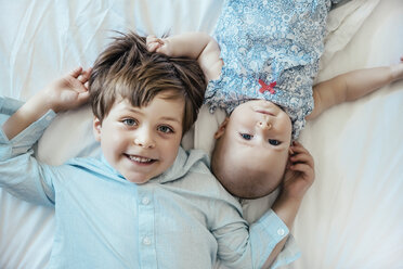 Kleines Mädchen und Bruder auf dem Bett liegend - MFF001964