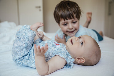 Baby girl and brother lying on bed - MFF001968