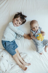 Kleines Mädchen und Bruder liegen nebeneinander auf dem Bett - MFF001971