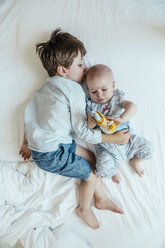 Kleines Mädchen und Bruder liegen nebeneinander auf dem Bett - MFF001972