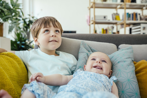 Kleines Mädchen und Bruder auf der Couch schauen nach oben, lizenzfreies Stockfoto