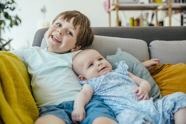 Smiling baby girl and brother on couch - MFF001979