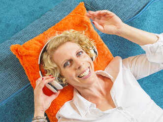 Portrait of smiling blond woman listening music with headphones - LAF001462