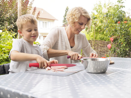 Mutter und Sohn bereiten das Essen auf der Terrasse zu - LAF001475