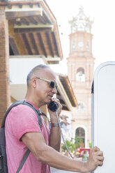 Mexiko, Puerto Vallarta, Tourist benutzt öffentliches Telefon vor der Kirche Unserer Lieben Frau von Guadalupe - ABAF001878