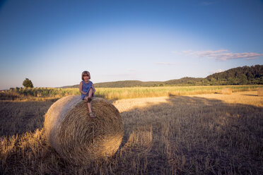 Little girl sitting on straw bale - LVF003764