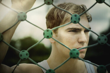 Portrait of young athlete standing at volleyball net - GDF000839