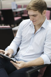 Young man sitting in coffee shop using digital laptop - GDF000846