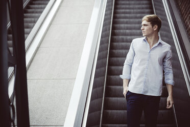 Young man standing on escalator - GDF000845