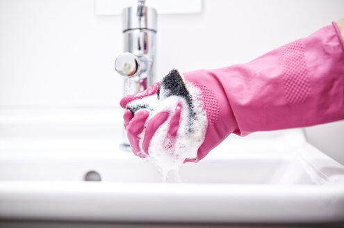 Frau reinigt Waschbecken mit Schwamm - MFRF000338