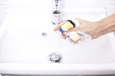 Woman cleaning bathroom sink with sponge - MFRF000341