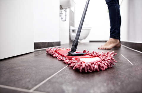 Woman wiping the floor in bathroom stock photo