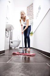 Woman wiping the floor in bathroom - MFRF000345