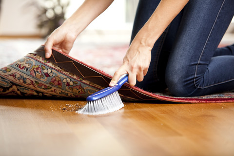 Frau kehrt unter den Teppich, lizenzfreies Stockfoto