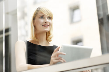 Portrait of smiling blond businesswoman with digital tablet - PESF000001