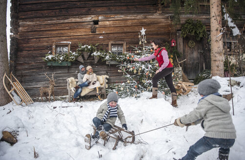 Österreich, Altenmarkt-Zauchensee, Familie vor einem Bauernhaus zur Weihnachtszeit - HHF005400