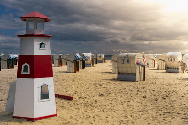 Deutschland, Schleswig-Holstein, Travemünde, kleiner hölzerner Leuchtturm und vermummte Strandkörbe am abendlichen Strand - FRF000298