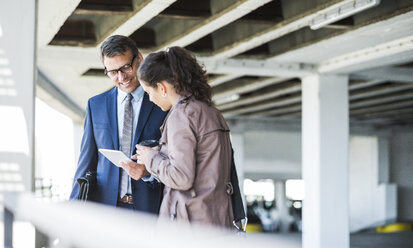 Mature businessman and young colleague in parking garage, using digital tablet - UUF005294