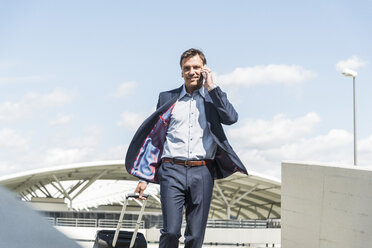 Businessman on business trip arriving with trolley - UUF005302