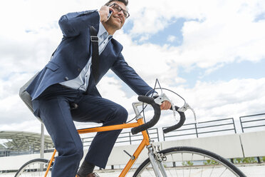 Geschäftsmann fährt Fahrrad und telefoniert - UUF005338