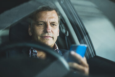 Mature businessman using smart phone in the car - UUF005252