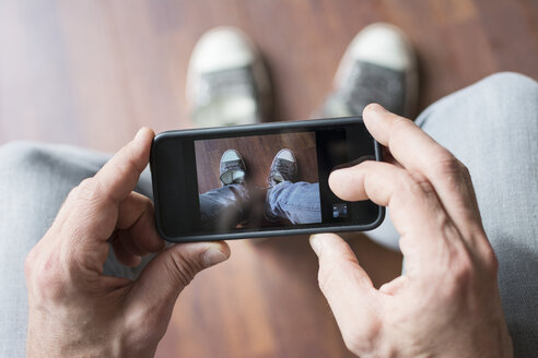 Mann fotografiert seine Schuhe mit dem Smartphone - ONF000844