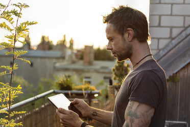 Germany, Berlin, Mature man on roof terrace using digital tablet - ONF000841