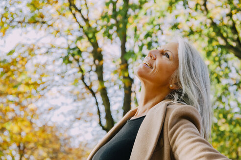 Glückliche Frau im herbstlichen Park mit Blick nach oben - CHAF001141