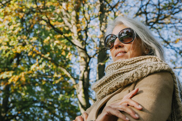 Portrait of smiling woman wearing scarf and sunglasses in a park - CHAF001145