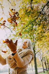 Woman throwing autum leaves in the air - CHAF001150