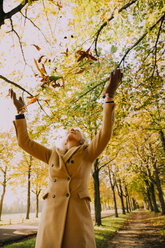 Woman throwing autum leaves in the air - CHAF001151
