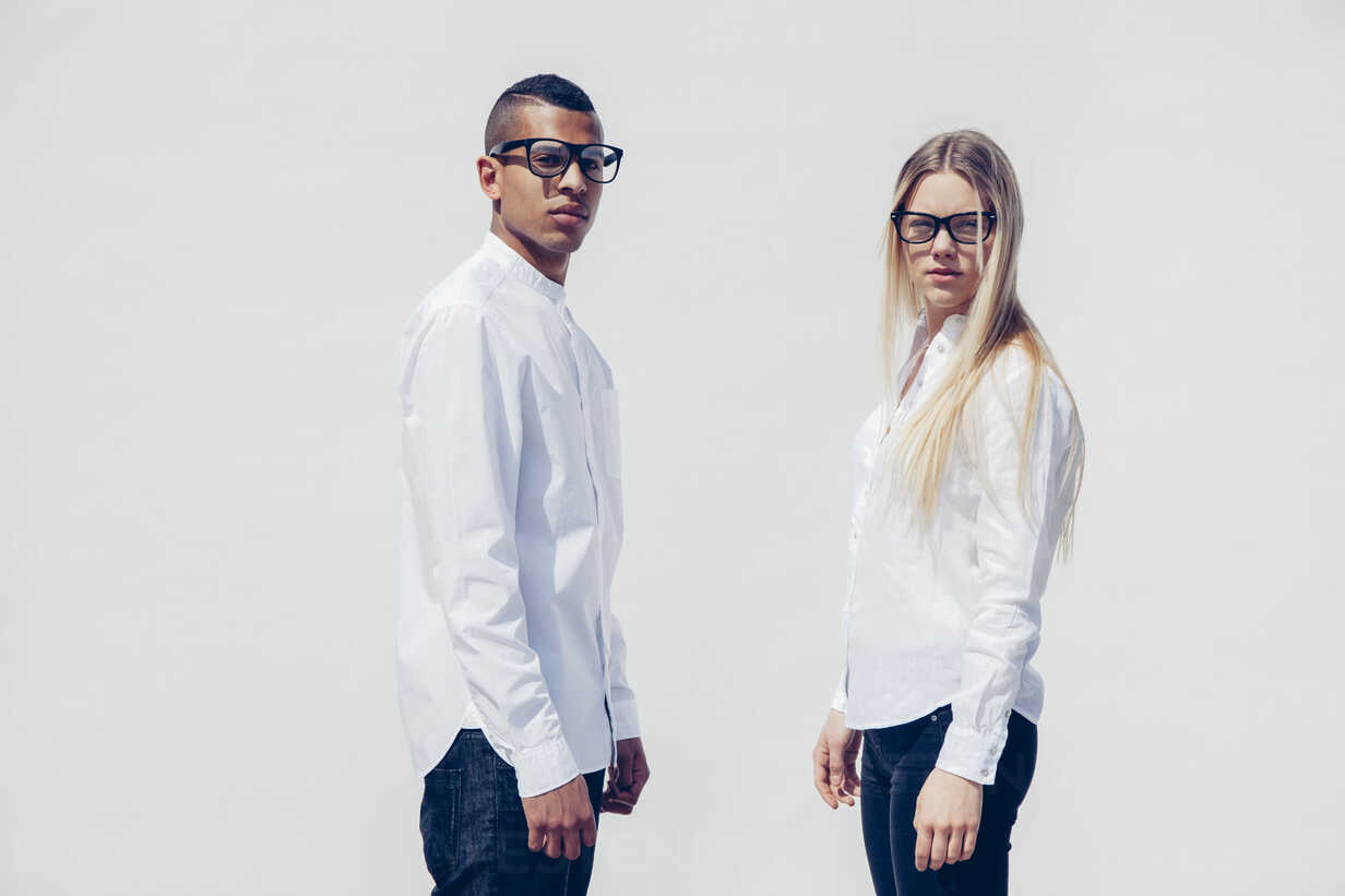 Portrait of stylish young couple wearing matching clothes in front of white  background stock photo
