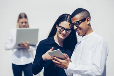 Stilvolles junges Paar mit Brille schaut gemeinsam auf ein Mini-Tablet - CHAF001175