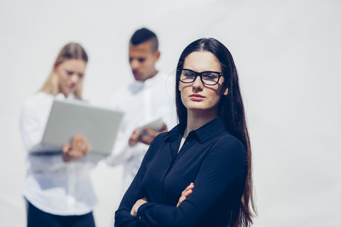 Porträt einer stilvollen jungen Frau mit verschränkten Armen und Brille, lizenzfreies Stockfoto