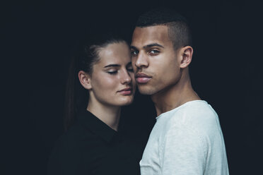 Porträt eines jungen Paares Kopf an Kopf vor einem schwarzen Hintergrund - CHAF001213