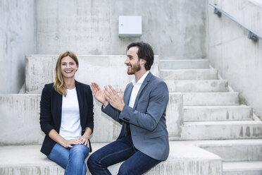 Two business people sitting on concrete steps - FMKF001750